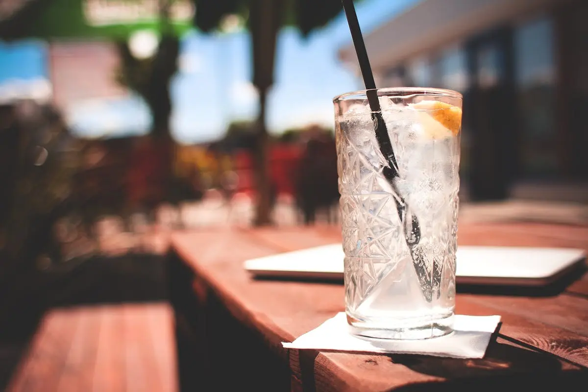 A cold gin and tonic with lemon slice on a summer patio, perfect for refreshment.