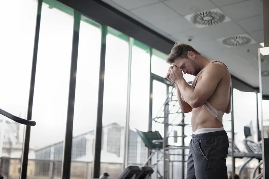 Sweaty tired muscular sportsman resting after workout in gym