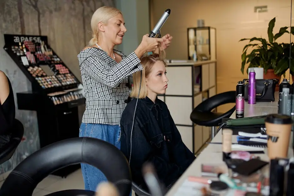 Side view of adult hairstylist straightening hair of client with iron in hairdressing salon