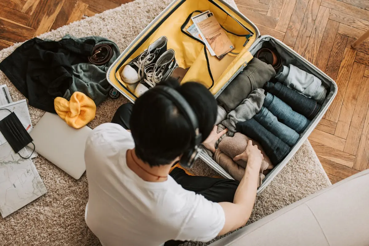 A Man on His Headphones while Packing His Clothes for an outdoor adventure