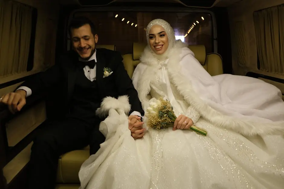 A happy bride and groom in a limousine, holding hands and smiling post-ceremony.