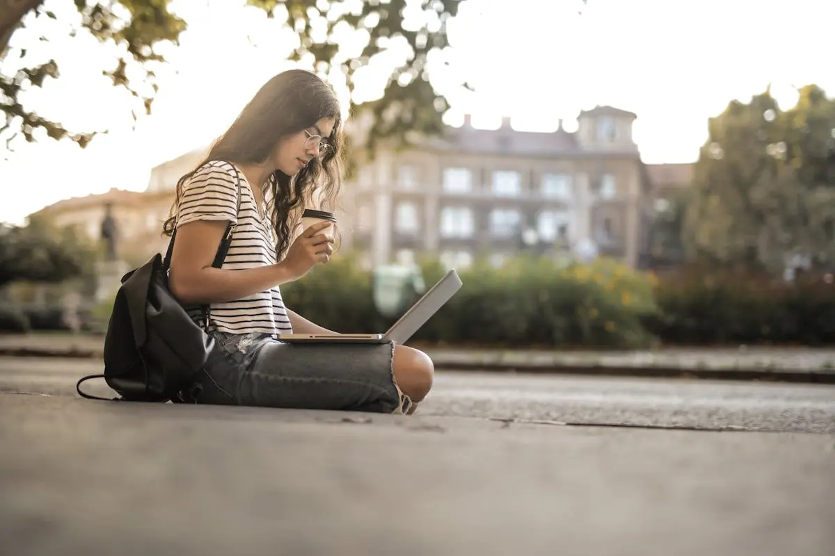 Woman in Black and White Stripe Shirt Sitting on Floor While Using Laptop