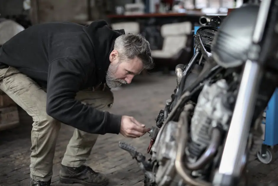 Side view of serious male master in untidy casual clothes standing near motorbike and checking details while working in garage