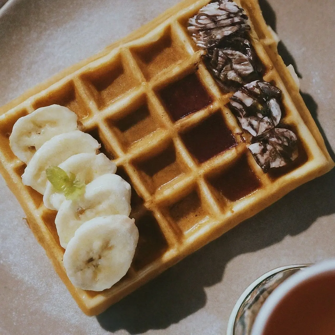 A freshly made waffle with tea and various topping options. 35mm stock photo