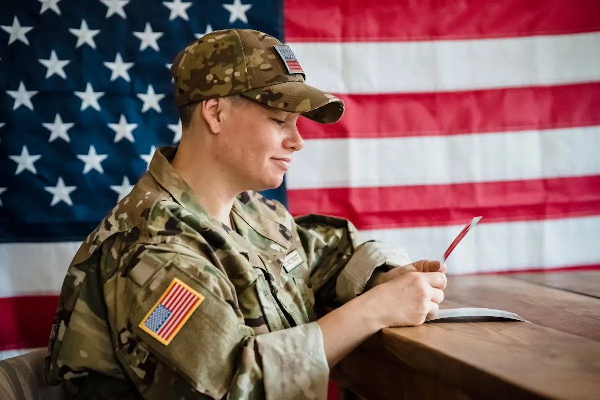 Soldier in uniform with US flag background, reflecting on memories.