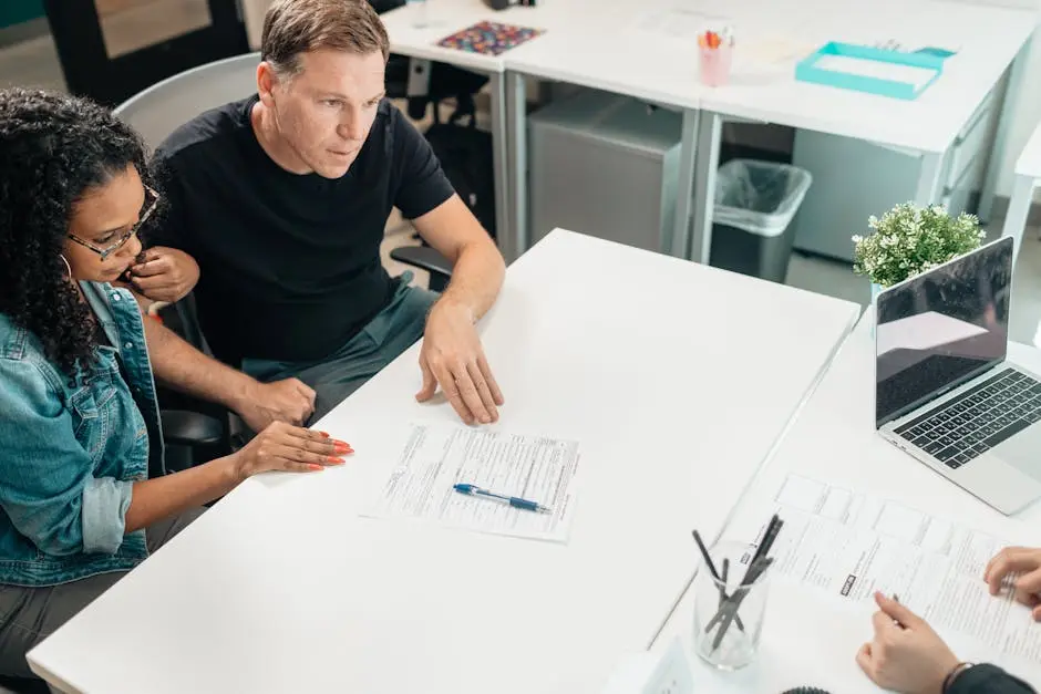 A couple discusses legal documents with a professional in a modern office setting.