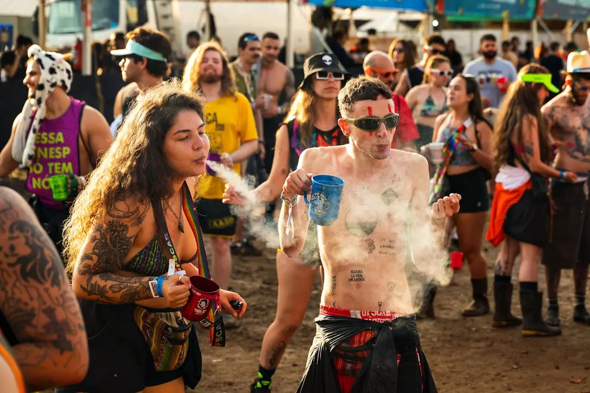 A diverse crowd at a lively outdoor festival with music, dancing, and colorful attire.