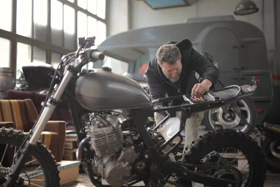 Male mechanic working on a motorcycle in an indoor workshop setting.