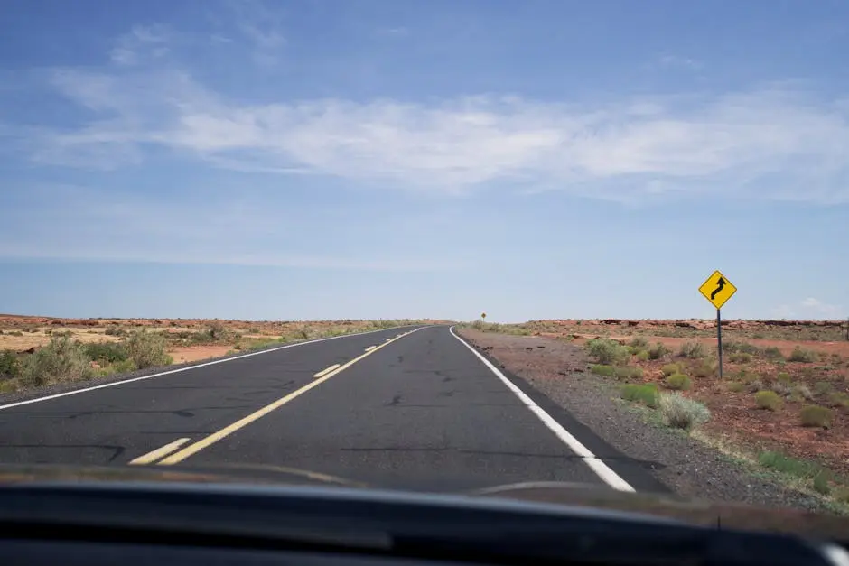 Endless road stretching through vast desert landscape under a clear sky, inviting travel adventures.