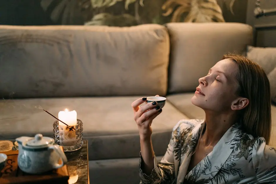 A woman enjoys a relaxing tea ceremony on her sofa with candles and incense.