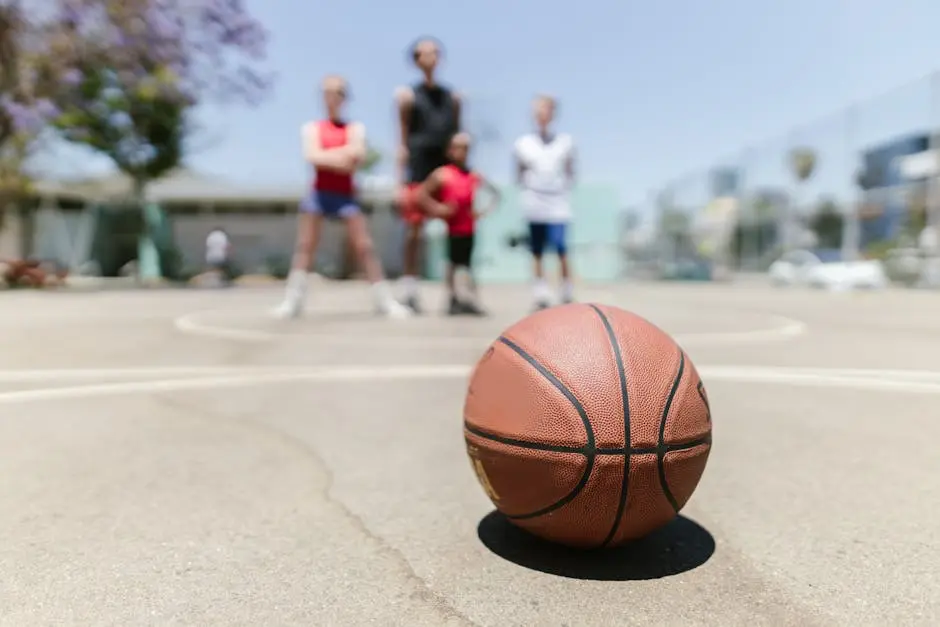 Close-up of basketball on court with blurred children in sports attire in background.