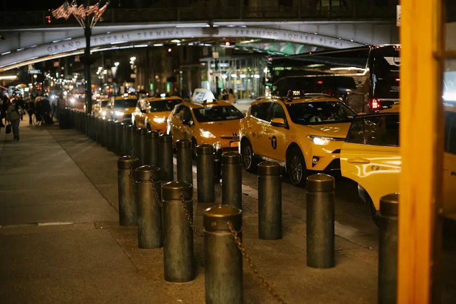 Row of modern shiny yellow taxis with glowing headlights parked at roadside near Grand Central Terminal in New York at night