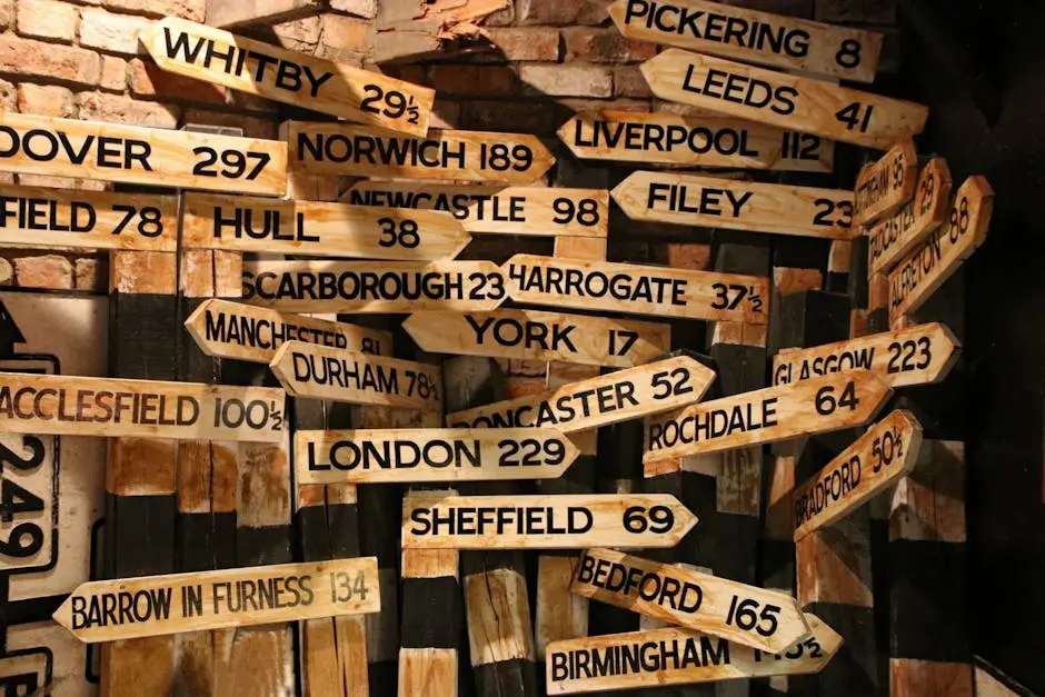 A collection of vintage wooden road signs showing distances to various UK towns and cities.