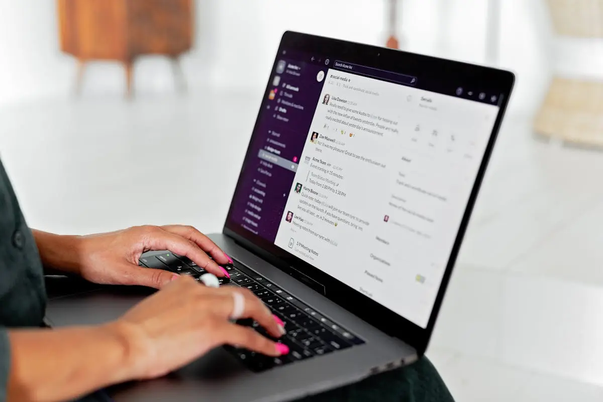 A woman types on a laptop using a messaging app in a modern office setting.