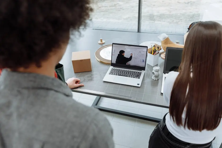 Two colleagues engaging in a remote online meeting at a desk with a laptop.