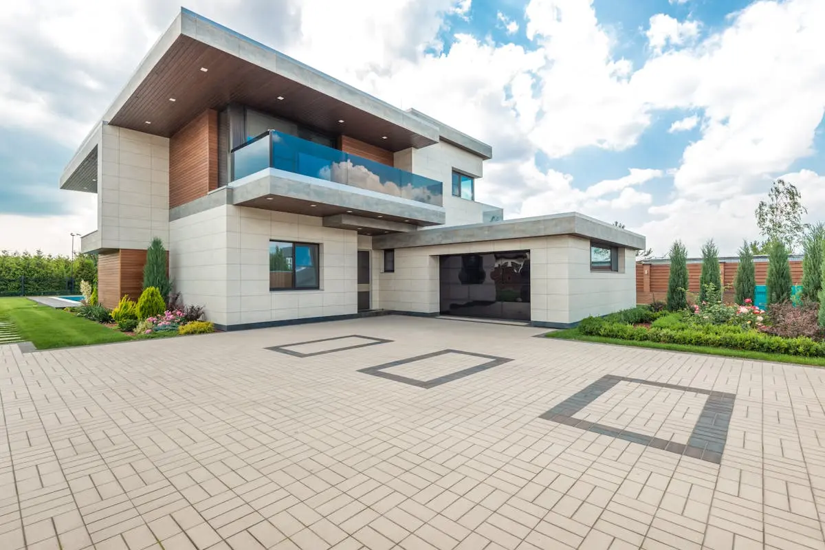 Elegant modern house exterior with lush greenery and ample driveway space.