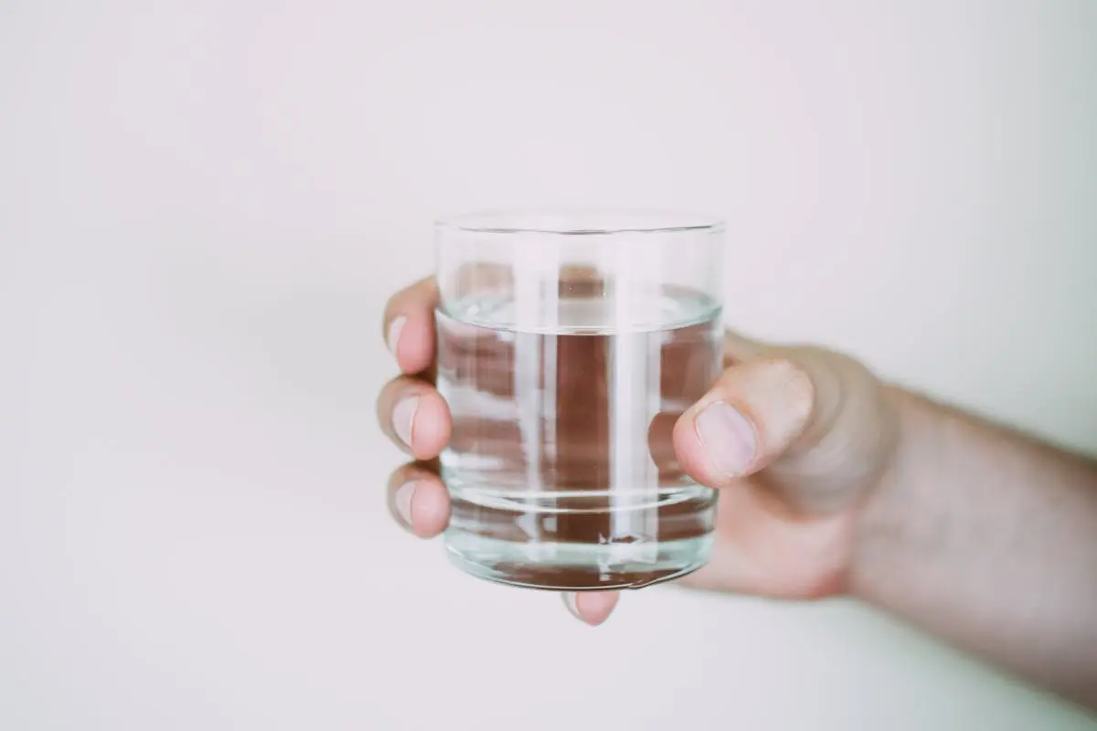 A close-up shot of a hand holding a clear glass of water, symbolizing refreshment.