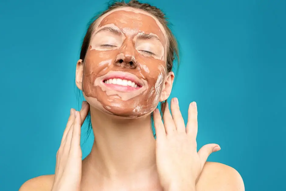 Close-up of a smiling woman with a clay facial mask, conveying relaxation and skincare routine.