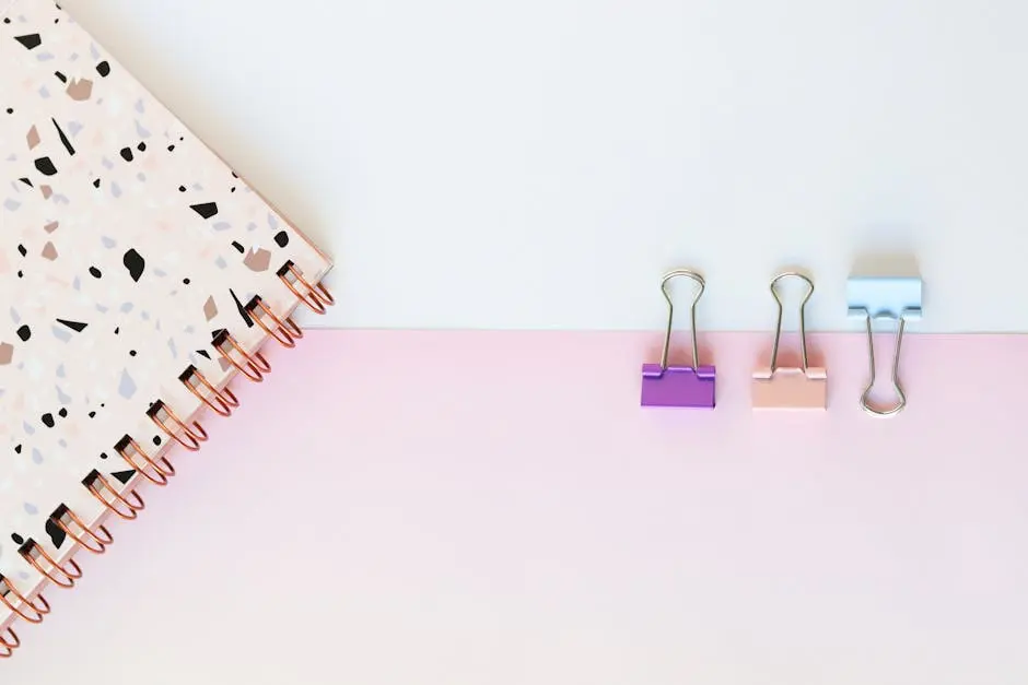 Aesthetic flat lay of pastel binder clips and terrazzo notebook. Ideal for office decor concepts.