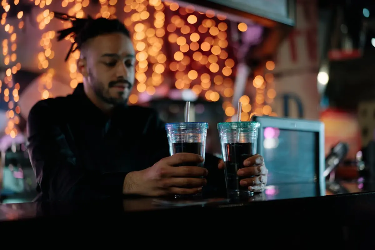 Man Holding Glasses of Drinks on a Counter