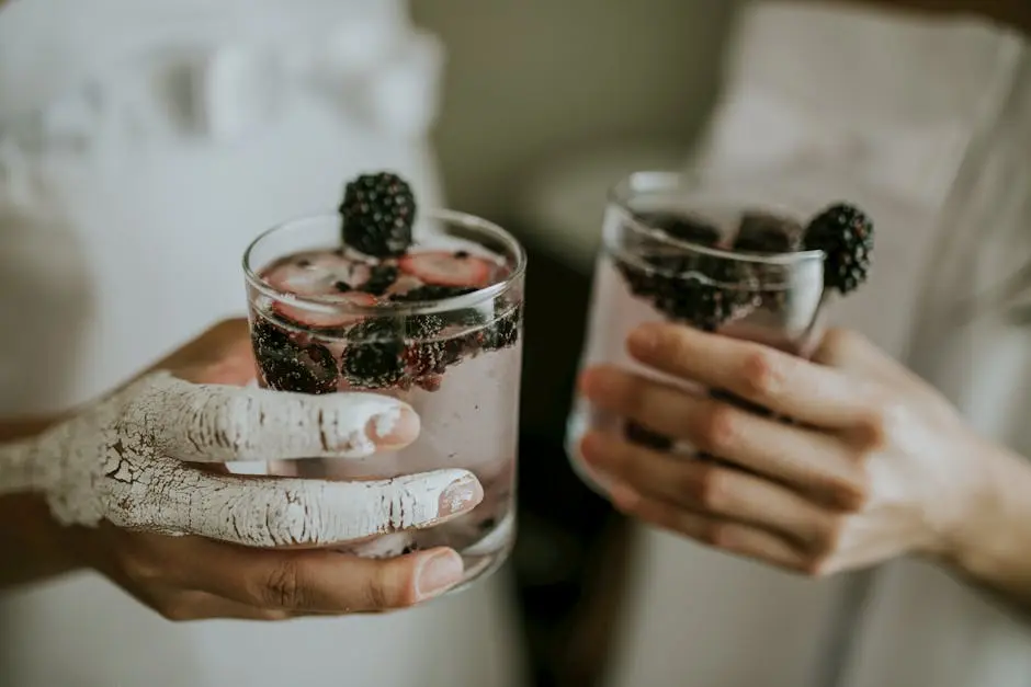 Close-up of hands holding blackberry-infused drinks, rich in detail and texture.