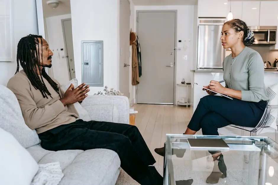 Therapist listens attentively to client during a mental health session in a contemporary office environment.