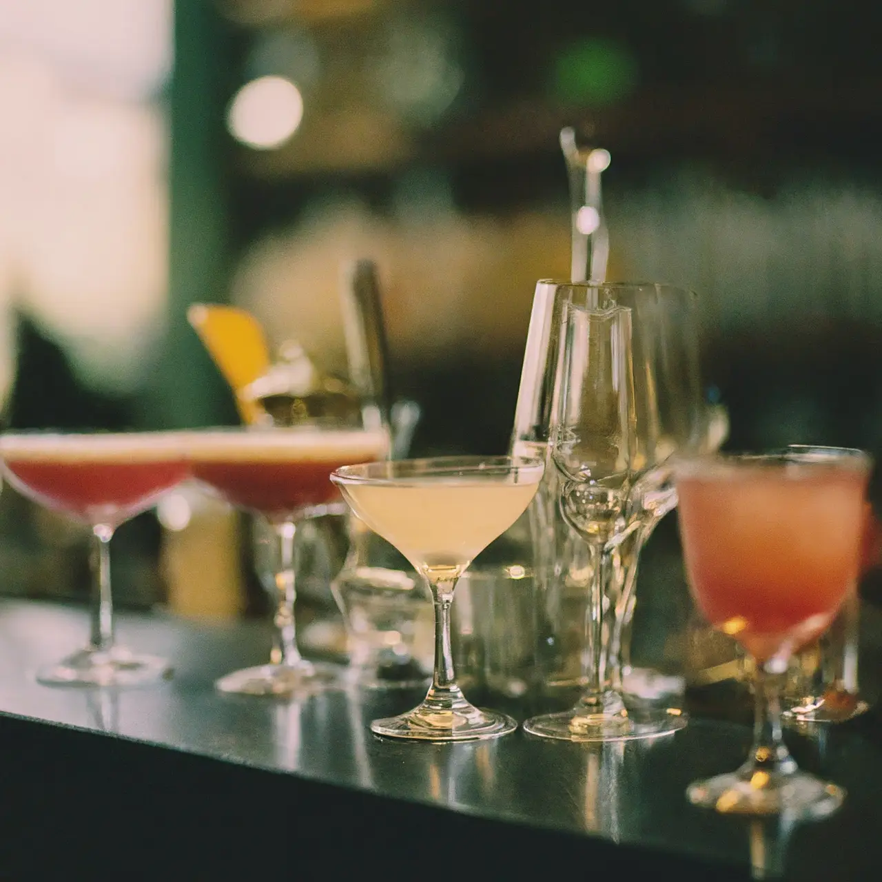 A variety of cocktail glasses arranged on a bar counter. 35mm stock photo