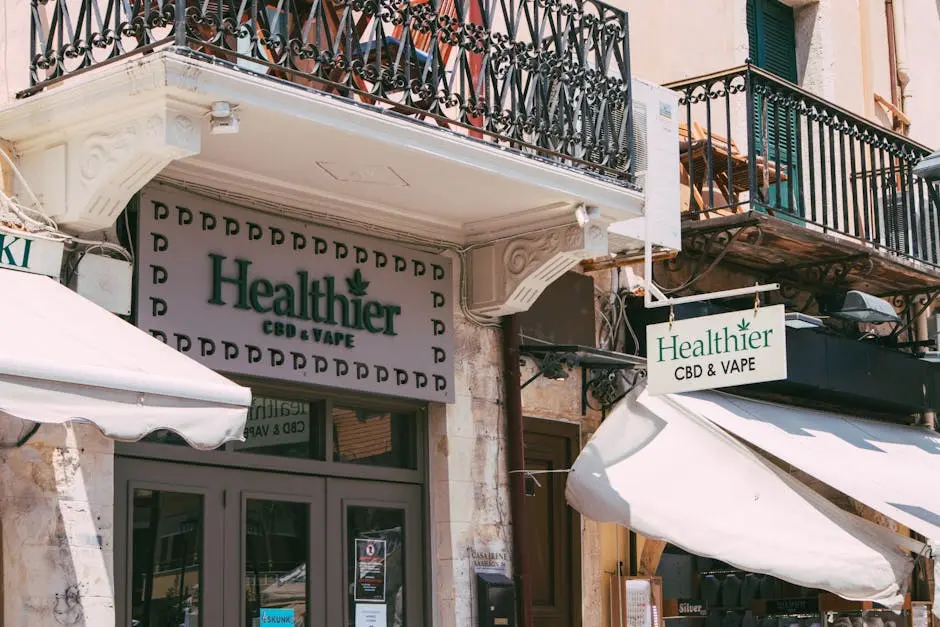 Street view of a CBD and vape store with decorative balcony in an urban area.