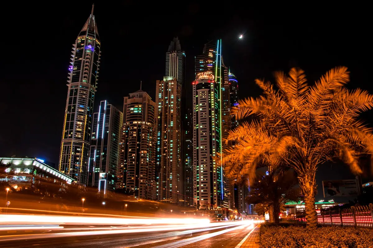 Stunning night view of Dubai’s illuminated skyscrapers and palm trees with light trails from passing cars.