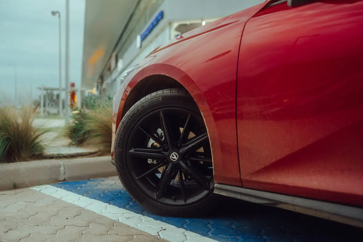 The wheel of a red car parked in a parking lot