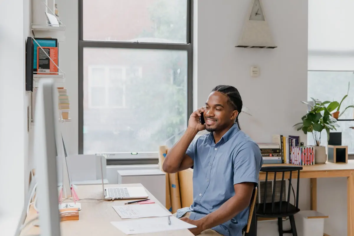 Adult man engaged in office work, speaking on phone, showcasing a professional environment.