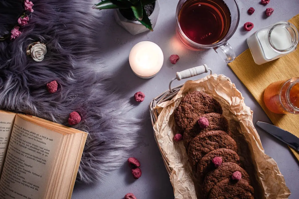 Inviting scene of cookies, tea, and candlelight for a relaxing evening read.