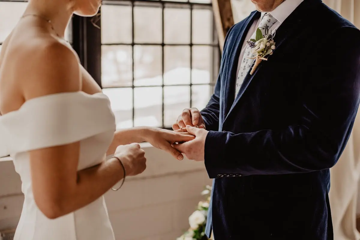 Couple exchanging rings during an intimate indoor wedding ceremony, symbolizing love and unity.