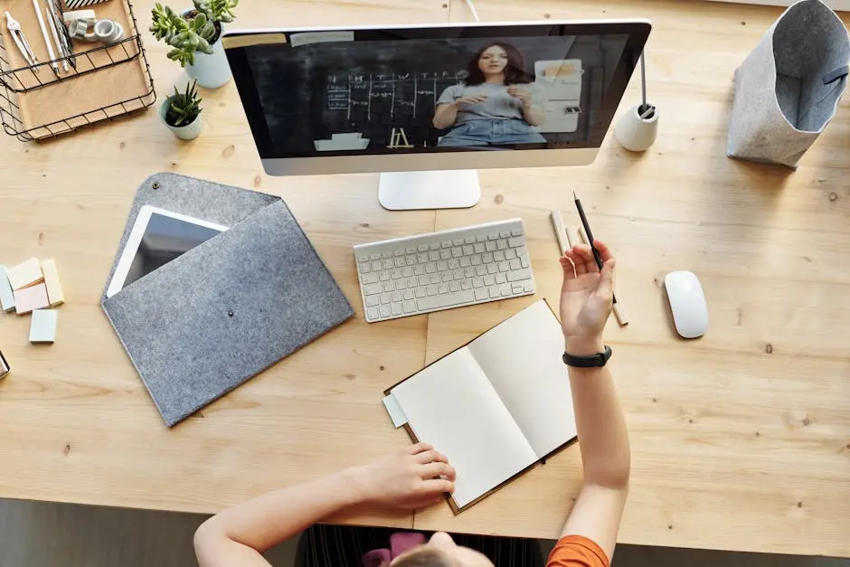 Teen girl actively learning in an organized home workspace via online class on a desktop computer.