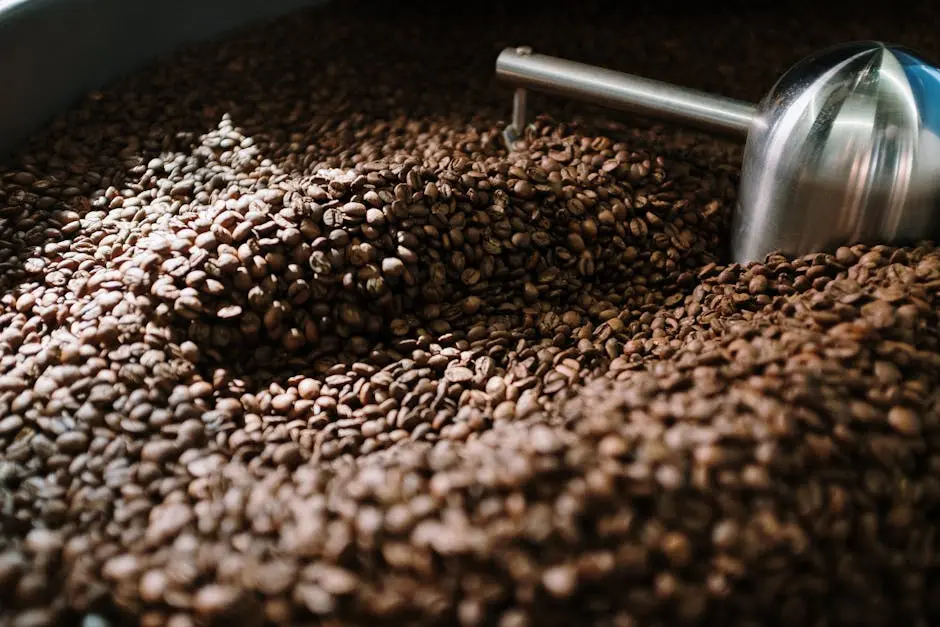 Detailed view of brown coffee beans being roasted in a steel machine, capturing the industrial process.