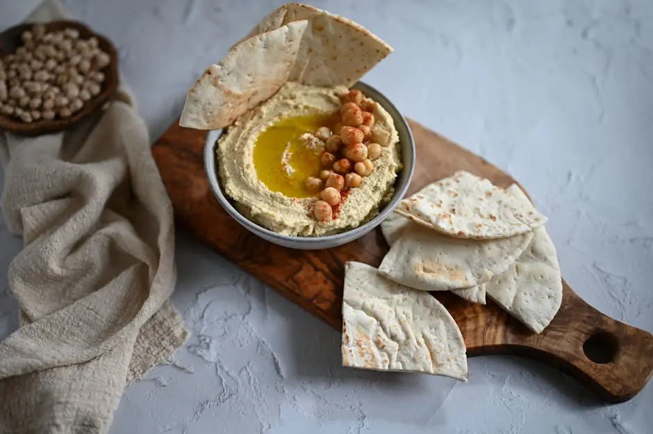 Delicious homemade hummus served with pita bread on a rustic cutting board, perfect for a healthy snack.