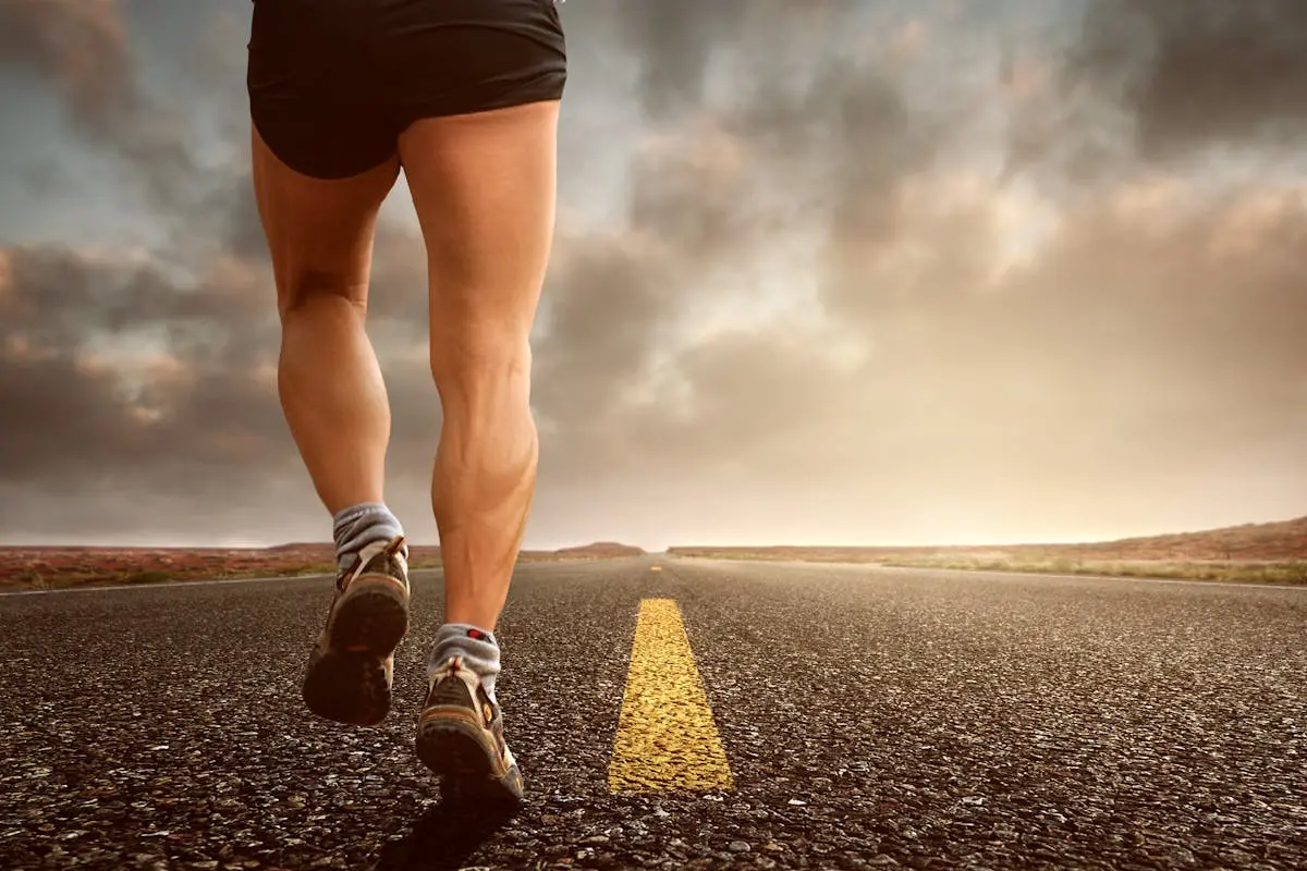 Runner’s legs on a road during a sunset, symbolizing endurance and outdoor fitness training.