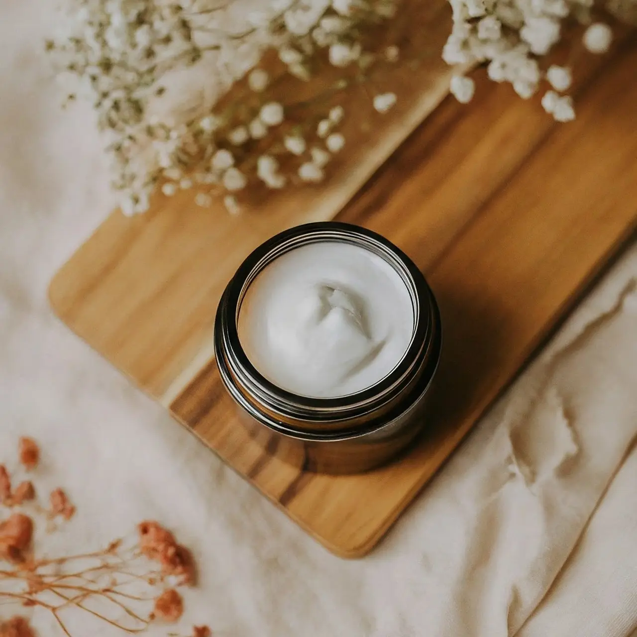 A jar of vegan firming cream with floral accents nearby. 35mm stock photo