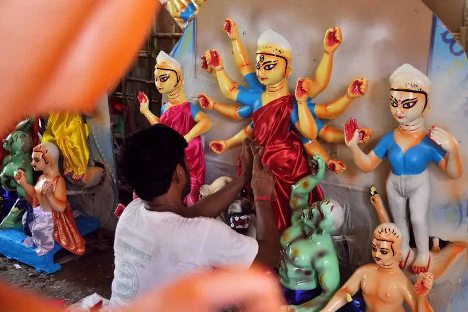 An artist carefully paints Hindu goddess sculptures, focusing on details and vibrant colors.