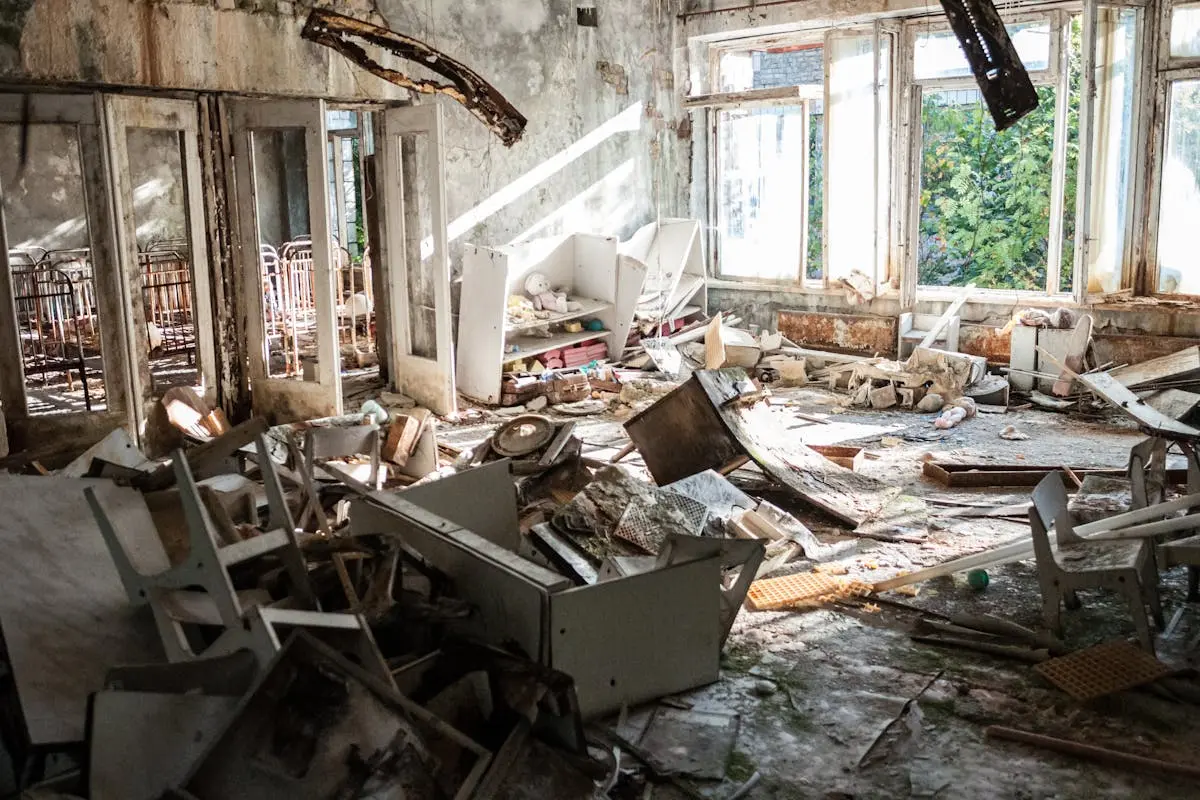 A desolate room filled with decayed furniture, debris, and broken windows, illustrating urban decay.