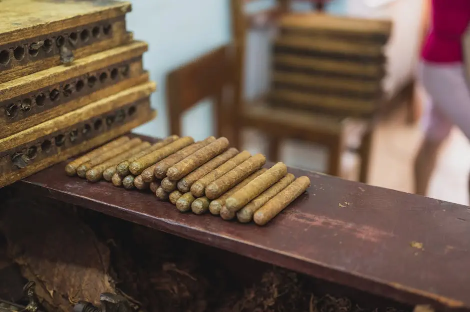 A collection of handmade cigars neatly arranged on a wooden table in a cigar factory.