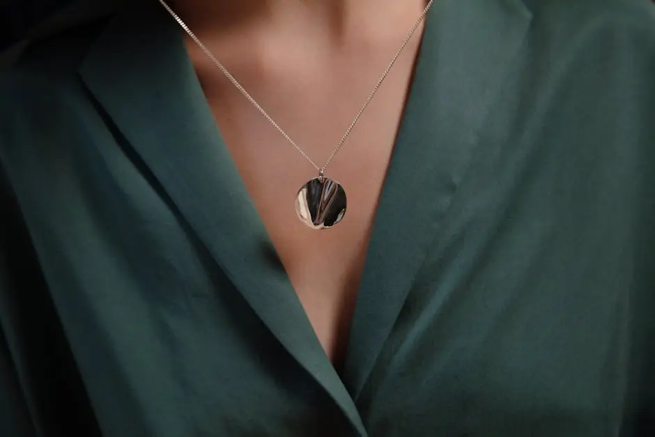 Close-up of a stylish silver necklace with a pendant, enhancing a green blouse for a classy look.