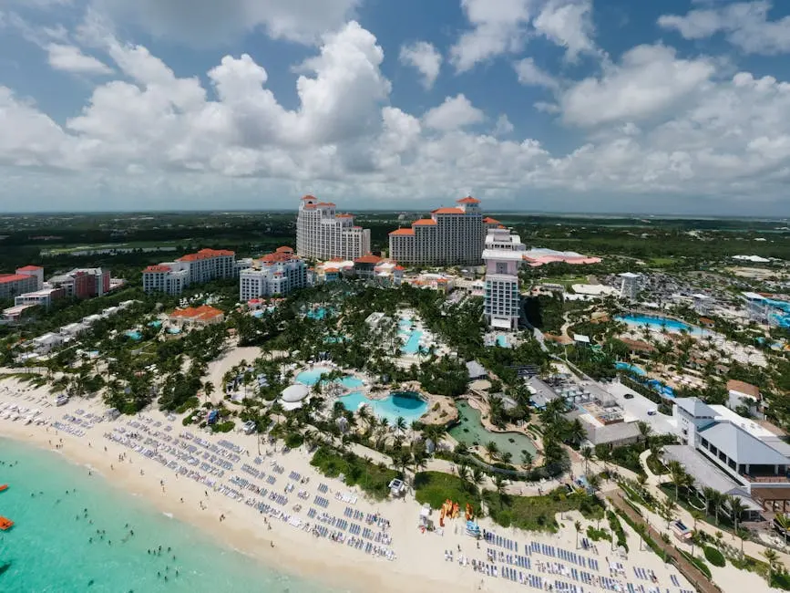 A stunning aerial shot of a luxury resort by the beach in the Bahamas, featuring pools and palm trees.