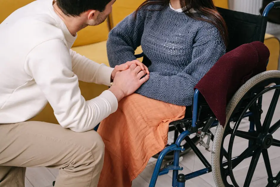 Man providing care and support to woman in a wheelchair indoors.