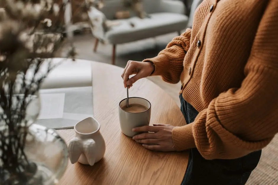 Woman stirs coffee in a cozy home setting, enjoying a warm morning routine.