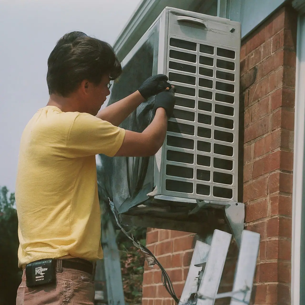 A technician repairing an air conditioning unit outside a house. 35mm stock photo