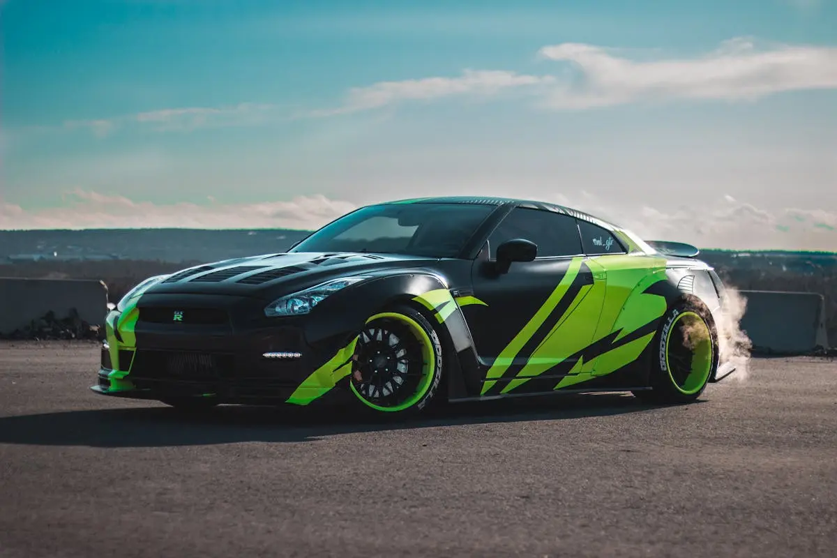 Modern tuned sports car with tinted windows drifting on asphalt road against cloudy blue sky