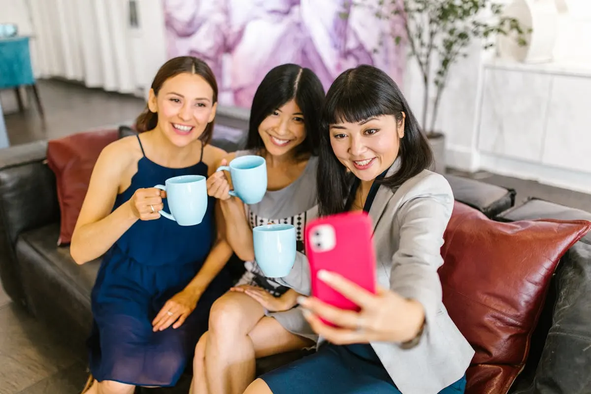 Three businesswomen enjoying a break and taking a selfie in a modern office setting.