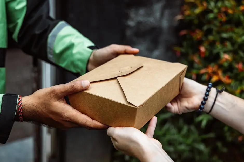 Close-up of a delivery person handing over a box to a customer outdoors.