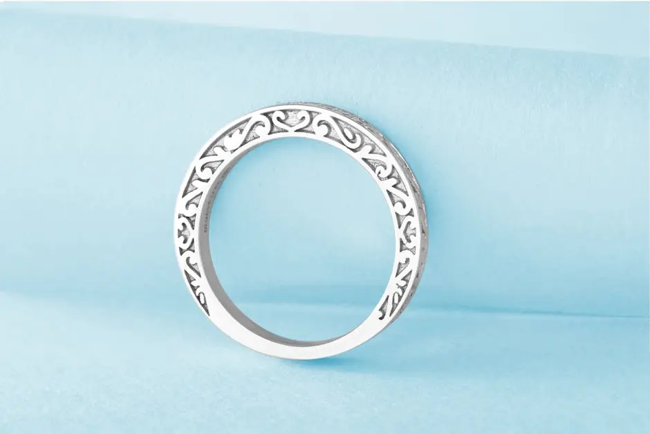 Close-up of a luxurious engraved silver ring on a soft blue backdrop, showcasing elegance.